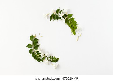 Round frame made of white flower buds and green leaves isolated. Flat lay, top view. Wedding concept.