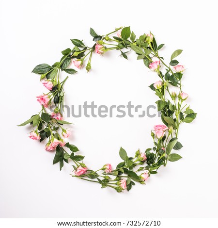 Round frame with pink flower buds, branches and leaves isolated on white background.