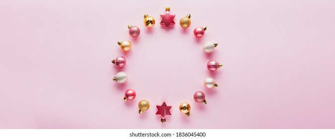 Round frame of Small pink and gold Christmas balls on pink background