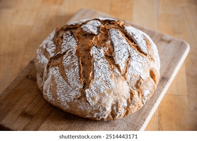 Round, freshly baked homemade bread with a golden, crispy crust. The bread has characteristic cuts on the surface, which add to its rustic charm. - Powered by Shutterstock