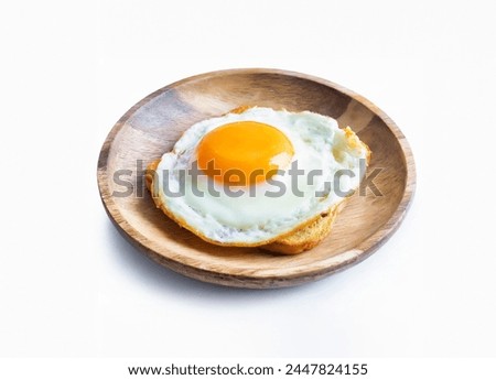 A round fried egg with a bright orange yolk sits on a plate