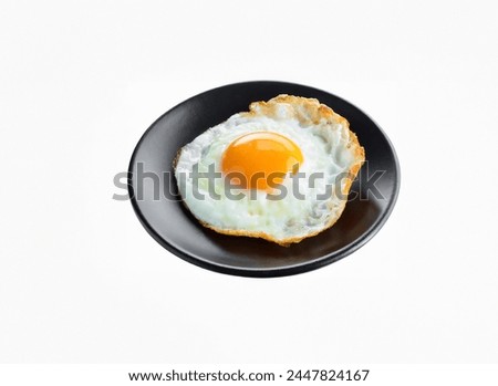 A round fried egg with a bright orange yolk sits on a plate