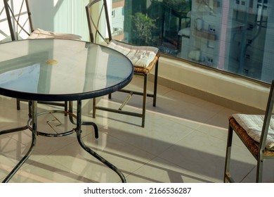 A Round Glass Top Table And Three Chairs On A Balcony, Summertime Shot