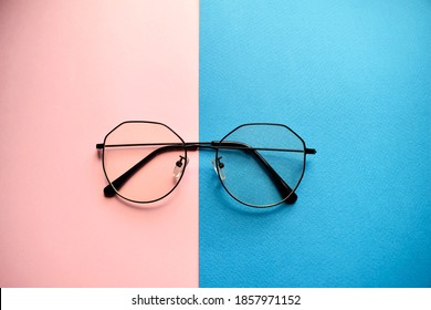 Round glasses in black frames on a pink and blue background. Optics - Shutterstock ID 1857971152