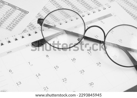 Round glasses and calendar on financial documents.
