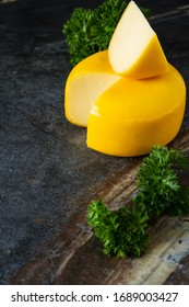 Round Gouda Cheese With Parsley. Dark Background