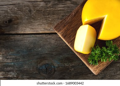 Round Gouda Cheese With Parsley. Dark Background