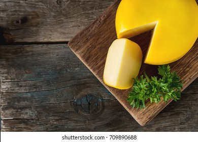 Round Gouda Cheese With Parsley. Dark Background