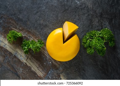 Round Gouda Cheese With Parsley. Dark Background