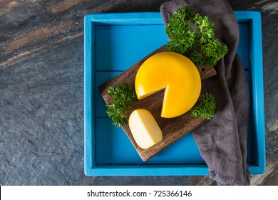 Round Gouda Cheese With Parsley. Dark Background