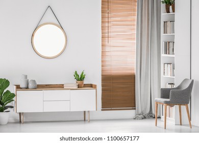 Round hanging mirror on the white wall above a cabinet in a bright contemporary room interior. Real photo. - Shutterstock ID 1100657177