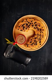 Round Homemade Cake On Wooden Tray On Black Background With Filter Coffee In Red Mug And Black Coffee Packaging Next To It. Top View Coffee Package Mockup. Coffee Bean Package Mockup