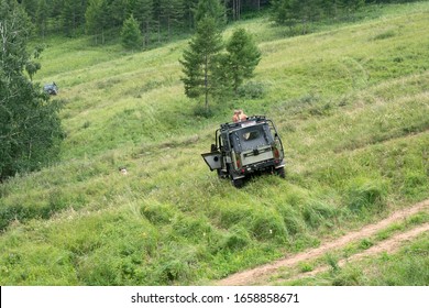 Round Lake, Krasnoyarsk Territory / RF - August 3, 2019: A Car With Children On The Roof Stands On A Steep Slope Of Forest Glade In The Summer.