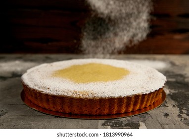  Round Lemon Cake With Powdered Sugar Lies On A Dark Textured Background