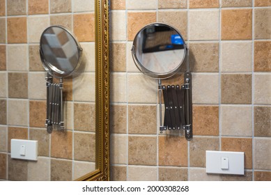 Round Magnifying Mirror With A Retractable Wall-mounted Stainless Steel Arm Hanging On The Wall In Toilet.