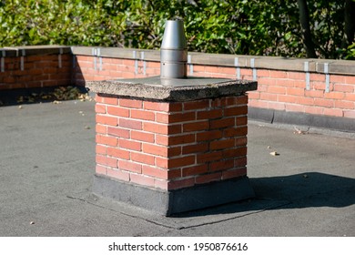 The Round, Metal Vertical Flue Of An Industrial Commercial Boiler Central Heating System On Top Of A Flat Roof