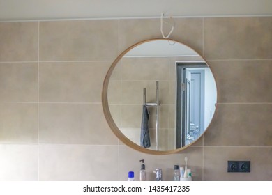 Round Mirror In Bathroom. Reflection With Bathroom Door And Towel.