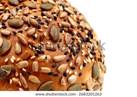 Round multigrain bread roll covered with pumpkin seeds, sunflower seeds, sesame, and black sesame.