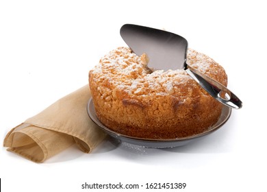 A Round Orange Cake With A Crumble Top And A Cake Knife Isolated On White