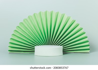 Round Pedestal With Paper Origami Fan On Light Green Background, Template For Product Presentation