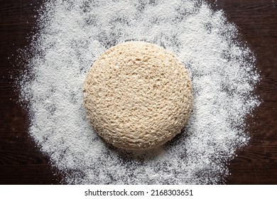 Round Piece Of Yeast-free Dough On A Floured Dark Table. Cellular Texture Of Yeast-free Dough. White Bread Texture. Mankind Oldest Staple Foods. Flat Lay, Copy Space.