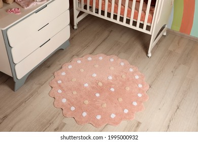 Round Pink Rug With Polka Dot Pattern On Wooden Floor In Baby's Room, Above View