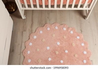 Round Pink Rug With Polka Dot Pattern On Wooden Floor In Baby's Room, Above View