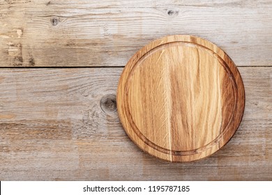 Round Pizza Board On Wooden Background. Space For Text
