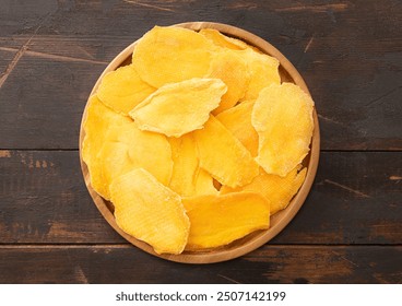 Round plate with dried mango pieces on wooden background.Top view. - Powered by Shutterstock