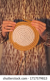 Round Raffia Crochet Panno In Female Hands. Handcraft, Hobby Concept: Holding A Wall Hanging And A Crochet Hook