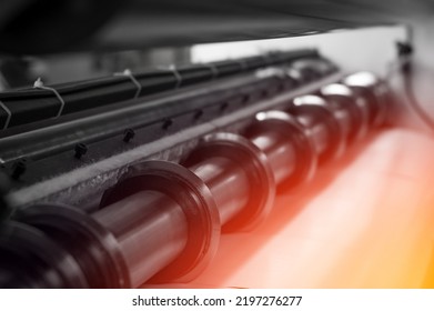 Round rotating knives for cutting paper and winding into separate rollers of self-adhesive material for typography. Machine for cutting polygraph paper. Equipment of paper industry. Selective focus - Shutterstock ID 2197276277