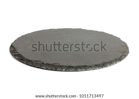 Round rustic black slate stone plate, isolated on white background.