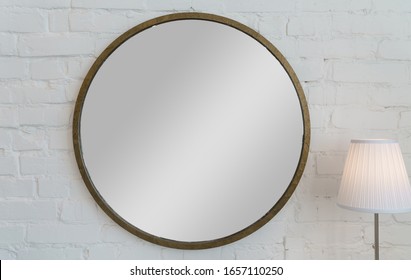 Round shape vintage golden frame mirror on white brick wall