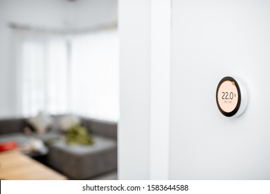 Round Smart Thermostat With Touch Screen Installed On The Wall Indoors. Smart Home Heating Regulation Concept. View With Copy Space