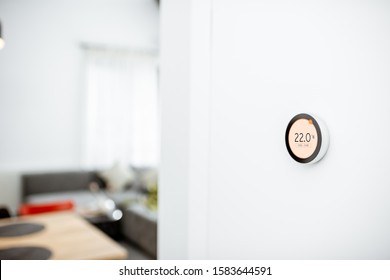 Round Smart Thermostat With Touch Screen Installed On The Wall Indoors. Smart Home Heating Regulation Concept. View With Copy Space
