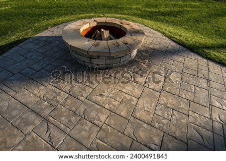 round stone fire pit on stamped concrete patio in grass yard