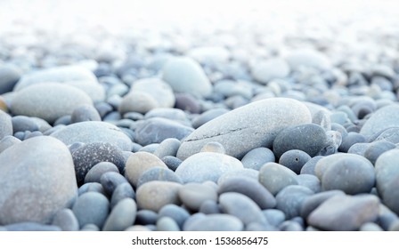 Round Stones On A Dry River Bed Outside In Nature. Smooth Pebbles With Light Gray Tones In Ambient Light.