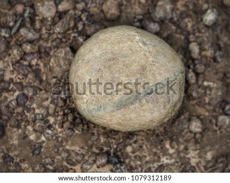 Round stones on the ground filled with small rocks, brown 
