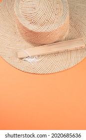 A Round Straw Hat And A Folding Hand Fan Isolated On A Peach Background With Free Space For Text- Concept For Hot Summer Weather