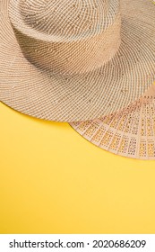 A Round Straw Hat And A Hand Fan Isolated On A Yellow Background With Free Space For Text- Concept For Hot Summer Weather