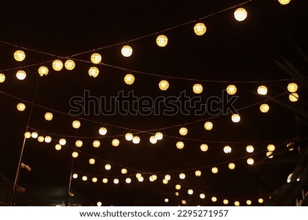 Round String lights in the night. Lamp garland of lanterns hanging in the park.