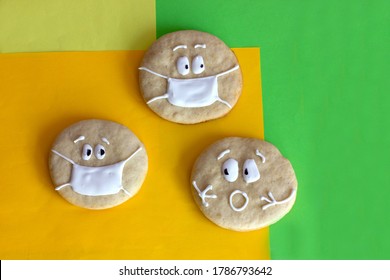 Round Sugar Cookies With Painted Faces In A Medical Mask, Surprised Face, Open Mouth, Icing, Icing, Quarantine, Yellow And Green Background