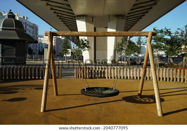 A round swing\
under the bridge in the city