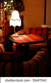 round table with checkered tablecloth and table lamp between two armchair in cafe