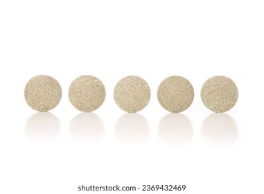 Round tablets in a row. Multiple green textured pressed wafer tablets or pills. Isolated multivitamins for dogs, food supplement. Selective focus. White background.