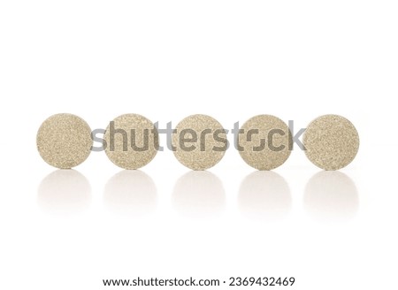 Round tablets in a row. Multiple green textured pressed wafer tablets or pills. Isolated multivitamins for dogs, food supplement. Selective focus. White background.