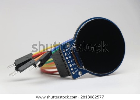 Round TFT LCD screen connected with jumper cables used in electronic projects
