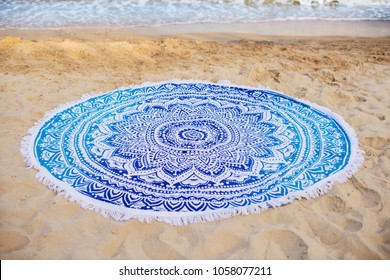 a round towel lies on the sand by the sea - Shutterstock ID 1058077211