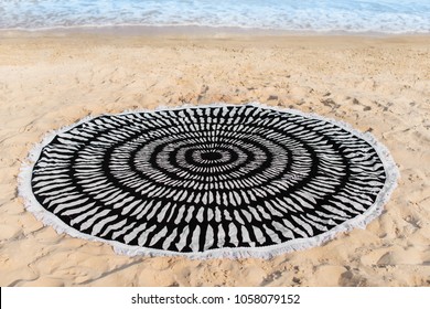 a round towel lies on the sand by the sea - Shutterstock ID 1058079152