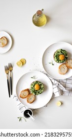 Round Tower Of Tartare With Raw Tuna, Avocado, Cucumber, Egg Yolk And Toasts On Plate On Table, Appetizing Healthy Vegetarian Dish, White Background, Top View, Flat Lay With Copy Space